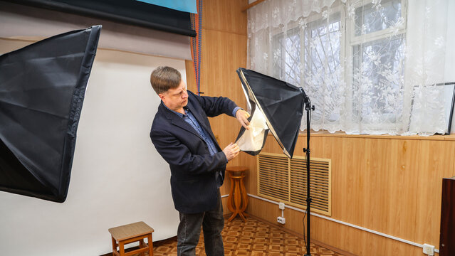 Male photographer inspecting and repairing a studio lighting equipment in a professional photo studio.