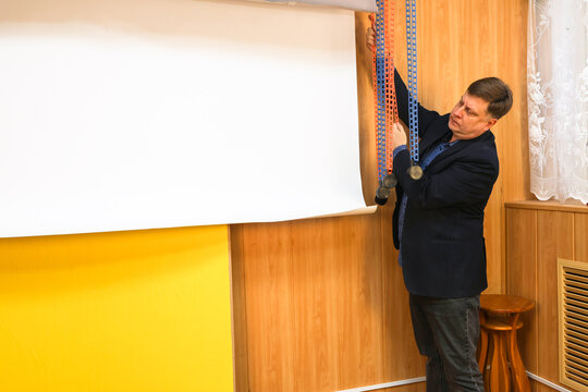 A male photographer lowers a white paper backdrop for a photo shoot in a professional studio.