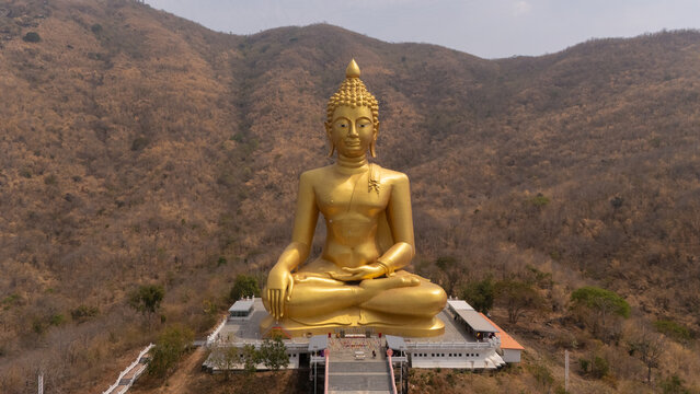 The large Buddha statue sits atop a beautiful mountain amidst nature.