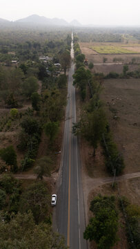 Aerial video of a rural road near a mountain with morning mist in Thailand.	