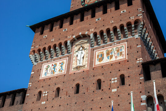 Ancient Tower Clock of Sforza Castle Brick Facade in Milan City Center Italy.