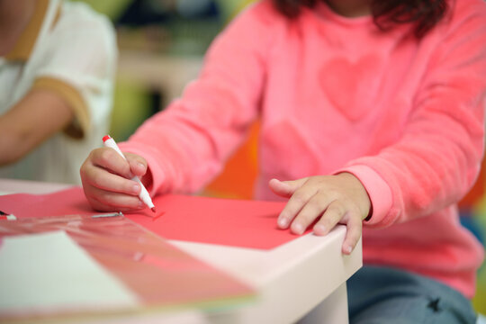 Close-up of a child drawing with a crayon during a classroom art activity, encouraging creativity, fine motor development, and early learning.