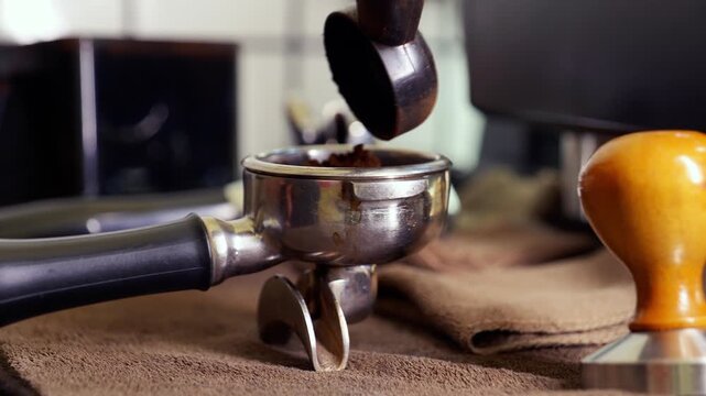 Close-up of freshly ground coffee being poured into an espresso portafilter, preparing for extraction.	