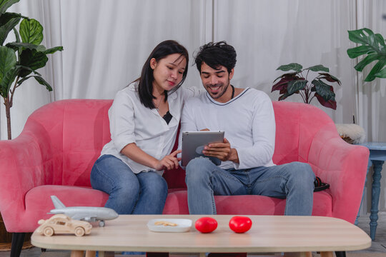 Happy husband and wife relaxing together at home while using tablet and enjoying quality time comfortable sofa.