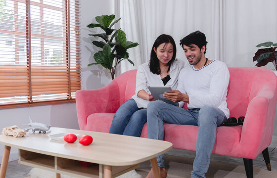 Happy husband and wife relaxing together at home while using tablet and enjoying quality time comfortable sofa.