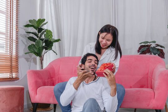 loving husband and wife exchanging thoughtful gift at home celebrating their relationship with happiness affection and togetherness.