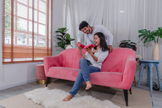 loving husband and wife exchanging thoughtful gift at home celebrating their relationship with happiness affection and togetherness.