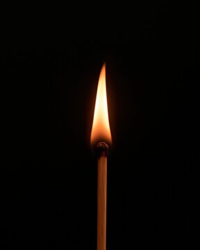 Une allumette enflamm&eacute;e br&ucirc;le avec une flamme vive sur fond noir