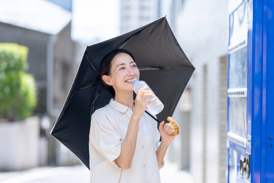 自販機でミネラルウオーターを買う女性