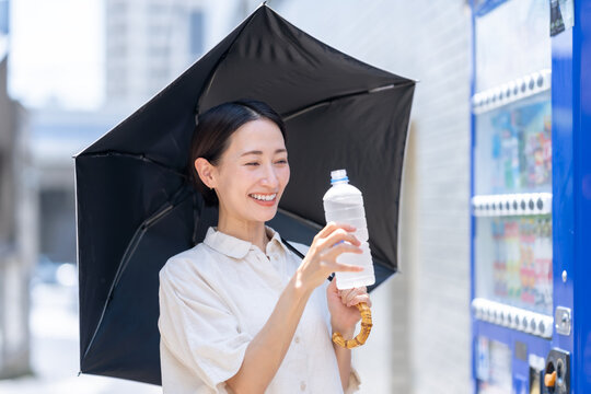 自販機でミネラルウオーターを買う女性