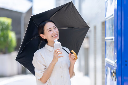 自販機でミネラルウオーターを買う女性