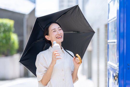 自販機でミネラルウオーターを買う女性