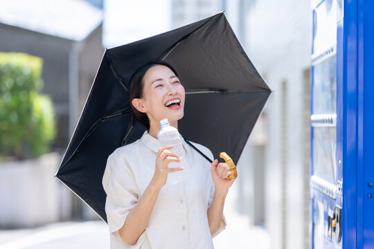 自販機でミネラルウオーターを買う女性