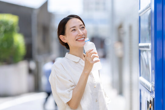 自販機で飲み物を買って飲む女性