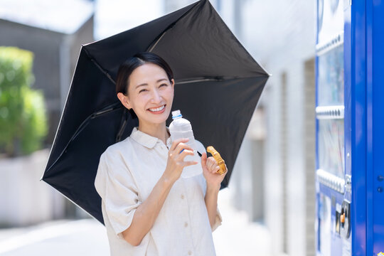 自販機でミネラルウオーターを買う女性