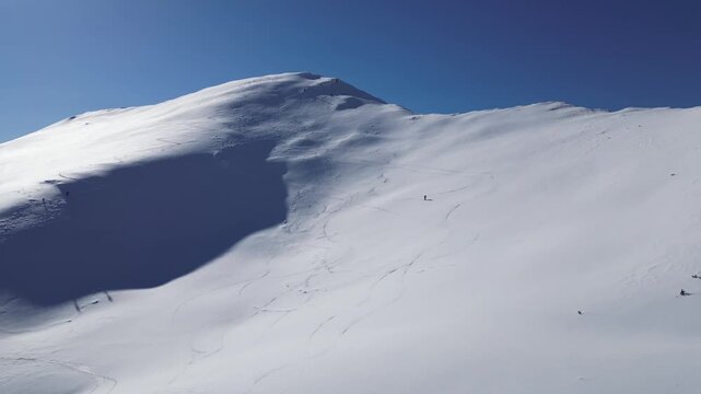 Drone View of Skiers Descending a Snow-Covered Mountain During Winter