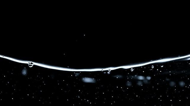 Fresh water exploding into scattered droplets with dramatic movement against black.