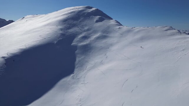 Drone View of Skiers Descending a Snow-Covered Mountain During Winter