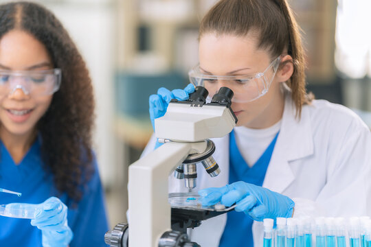 Diverse Female Scientists Conducting Research with Microscope and Chemical Flasks in Laboratory