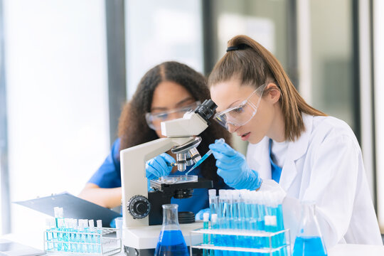 Diverse Female Scientists Conducting Research with Microscope and Chemical Flasks in Laboratory