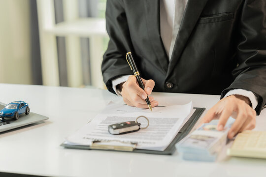 Businessman Signing Car Loan or Vehicle Insurance Contract with Money and Key on Desk
