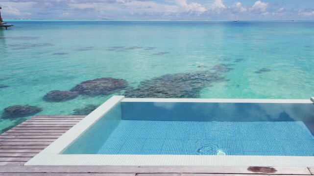 Pool Beach Vacation Background. Infinity pool over tropical ocean coral lagoon holidays vacation background in Slow motion shot. Raw unedited video of real pool.