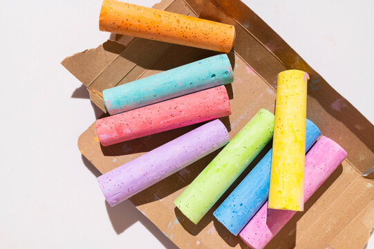 Brightly colored crayons on cardboard packaging against light background with space for text top view. Crayons for drawing, crafts, and school supplies.