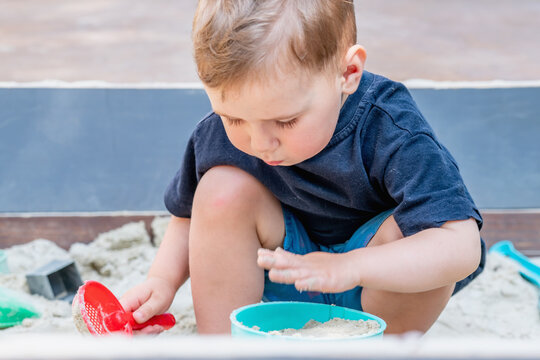 Toddler focused on a simple sandbox activity during summer playtime.