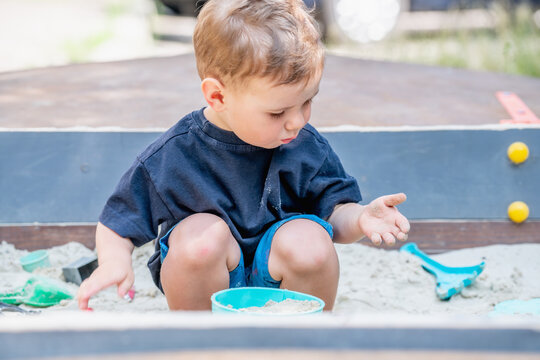 Little boy discovering the joy of independent play in the sand.