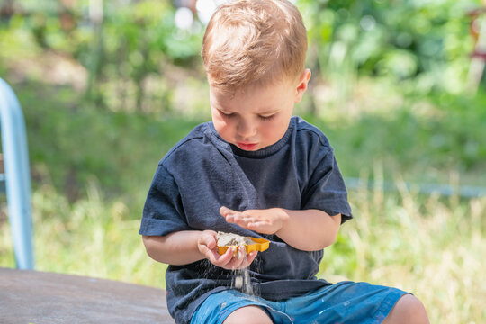 Little boy exploring sand with his hands during outdoor play.