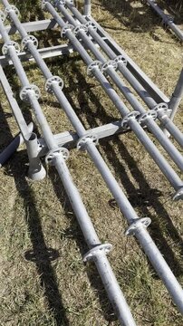 Galvanized metal scaffolding pipes arranged on dry grass. Construction equipment inspection and modular framework assembly concept for industrial work