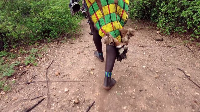 Close up of the legs of a Hamar tribe woman as she walks with bells on her legs in the Omo Valley of Ethiopia.