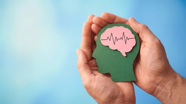 Hands holding a paper cutout of a human head with a brain and heartbeat