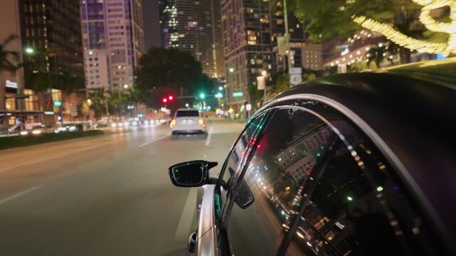 Black sports car speeding on highway with miami city lights and skyscrapers in background