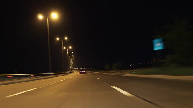 Car driving on night highway with street lights