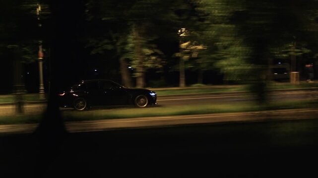 Dark luxury sedan speeding on a road at night, creating motion blur