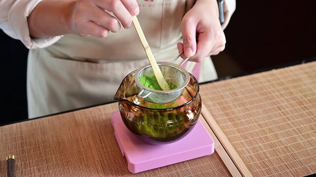 Someone sift Matcha powder through a sifter into a bowl to remove any clumps. Matcha is a finely ground powder made from shade-grown green tea leaves.