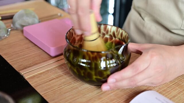 Someone using a bamboo whisk for whisking Matcha powder for drink.