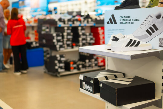  Footwear including Adidas shoes is displayed on a shelf in a retail store