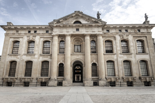 View of the neoclassical Clarendon Building with its grand columns, symmetrical windows, and statues on the roof in Oxford, England, United Kingdom.
