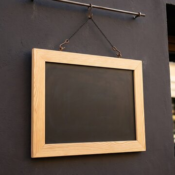 Blank wooden chalkboard hanging on a dark wall