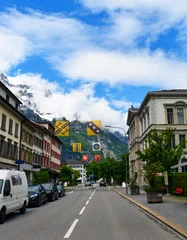 Blick entlang der Hauptstrasse in Glarus mit historischen Gebäuden und bunten Wappenbannern vor den Glarner Alpen © Ilhan Balta
