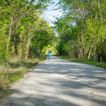 Distant male cyclist is riding a folding bike on Katy Trail near Rocheport, Missouri, spring scenery. The Katy Trail is 237 mile bike trail converted from an old railroad.