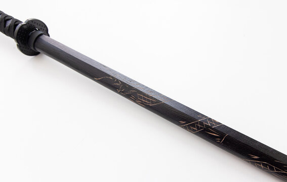 Closeup of a black wooden bokken with intricate carved patterns