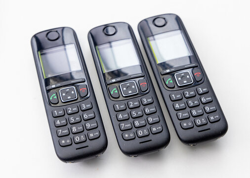 Three Identical Black Cordless Phones on a Clean White Background