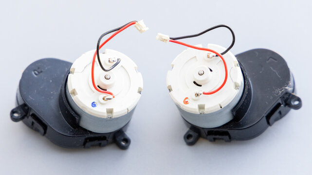 Two Small Electric DC Motors With Wires and Connectors on a Light Background