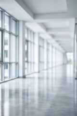 Fototapeta premium Empty modern office hallway with large windows and reflective floor, creating a bright minimalist atmosphere.