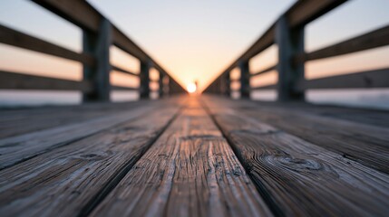 Obraz premium Low angle view of weathered wooden pier planks leading towards a bright sunset on the horizon with blurred railings
