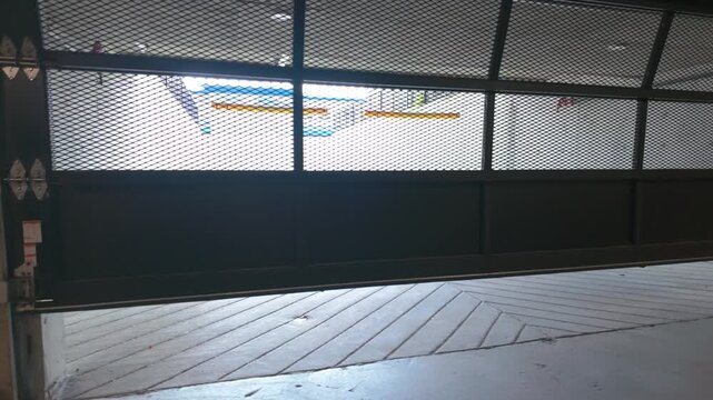 Industrial mesh security gate closing in underground parking garage structure