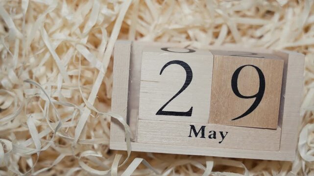 Wooden calendar blocks showing date May 29 on natural wood shavings background
